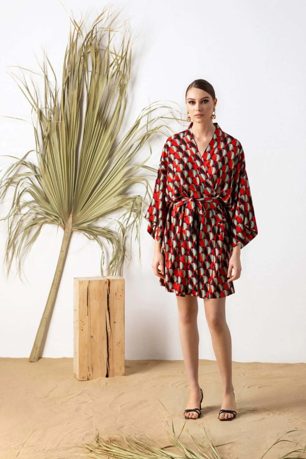 Woman wearing short multicolored kimono wrap dress in red white and blaqck colors by House of Azoiia